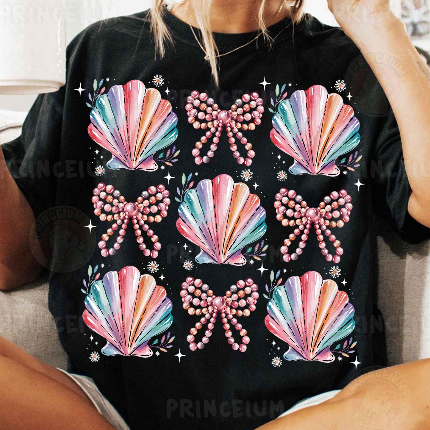a woman sitting on a couch wearing a black shirt with pink bows and pearls