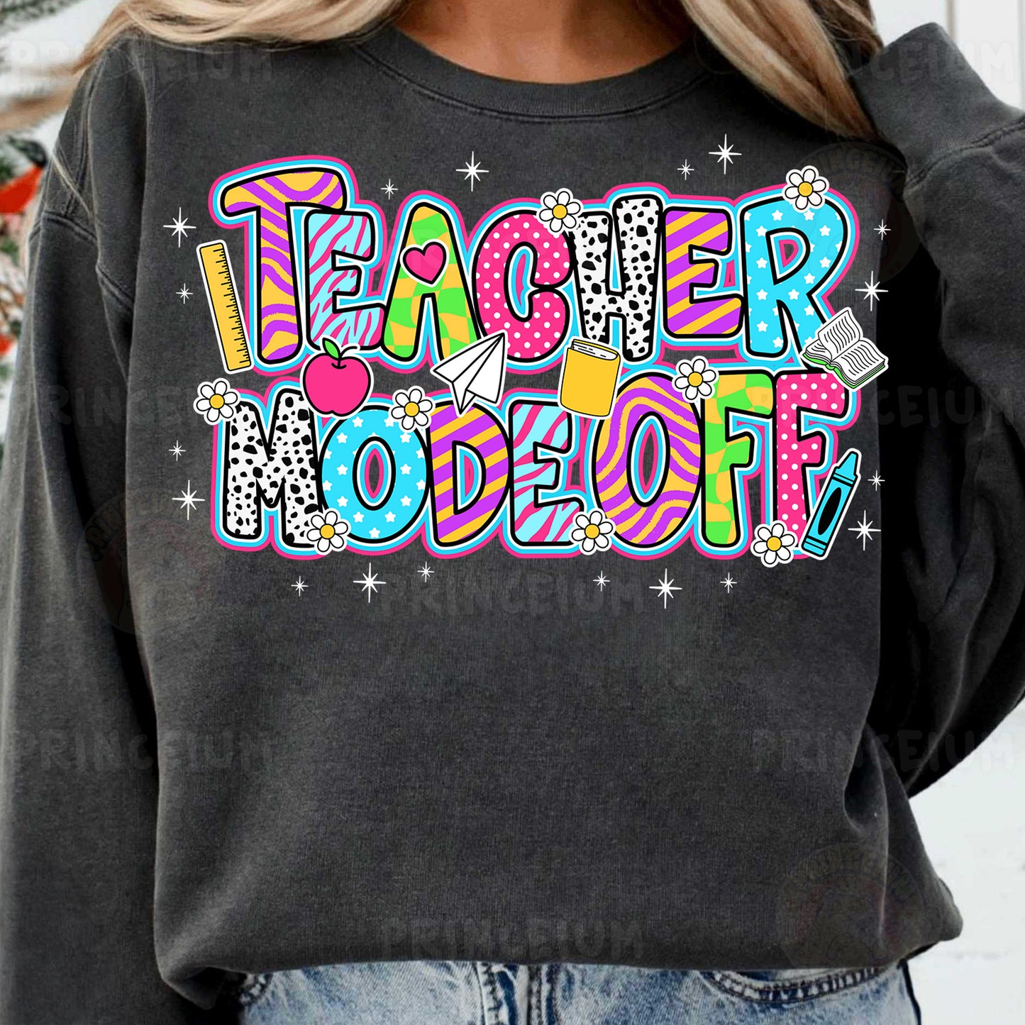 a woman wearing a black teacher sweatshirt with colorful lettering