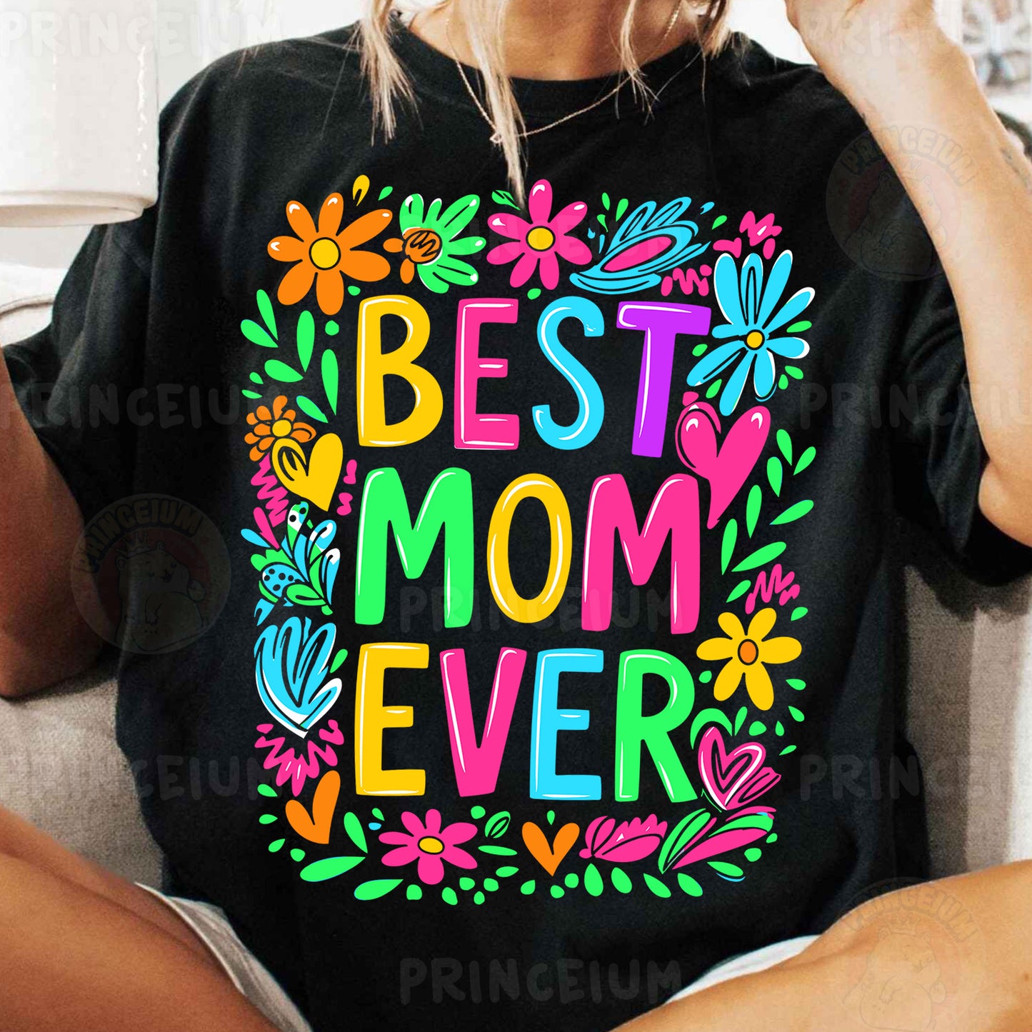 a woman sitting on a couch wearing a t - shirt that says best mom ever