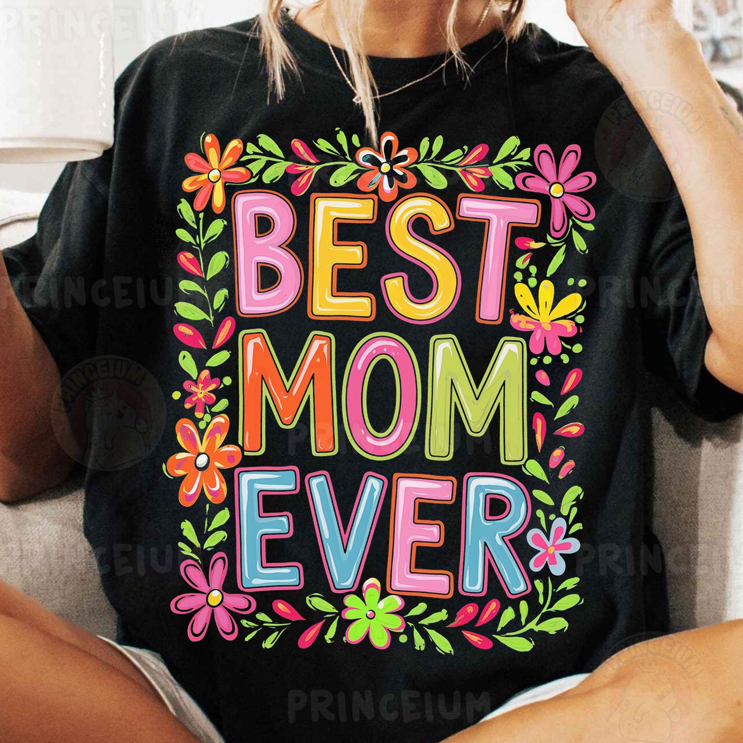 a woman sitting on a couch wearing a t - shirt that says best mom ever