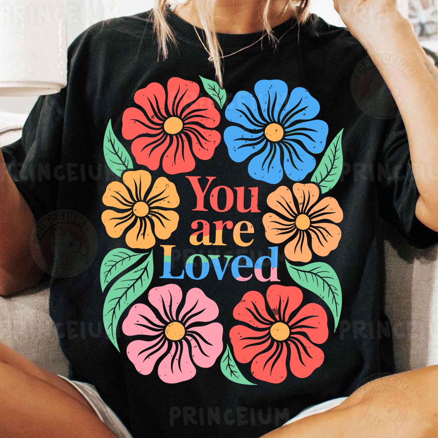 a woman sitting on a couch wearing a t - shirt that says you are loved