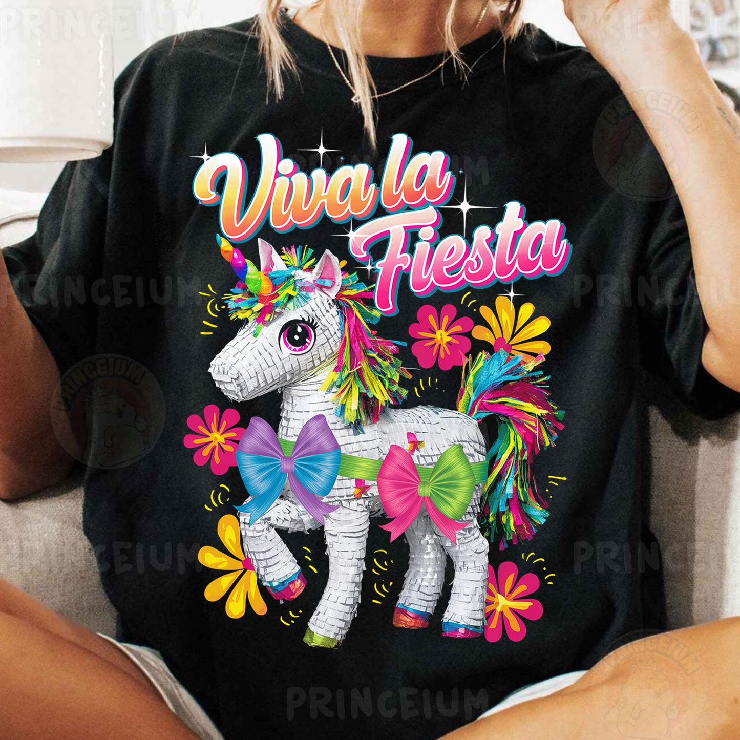 a woman sitting on a couch wearing a black shirt with a unicorn on it