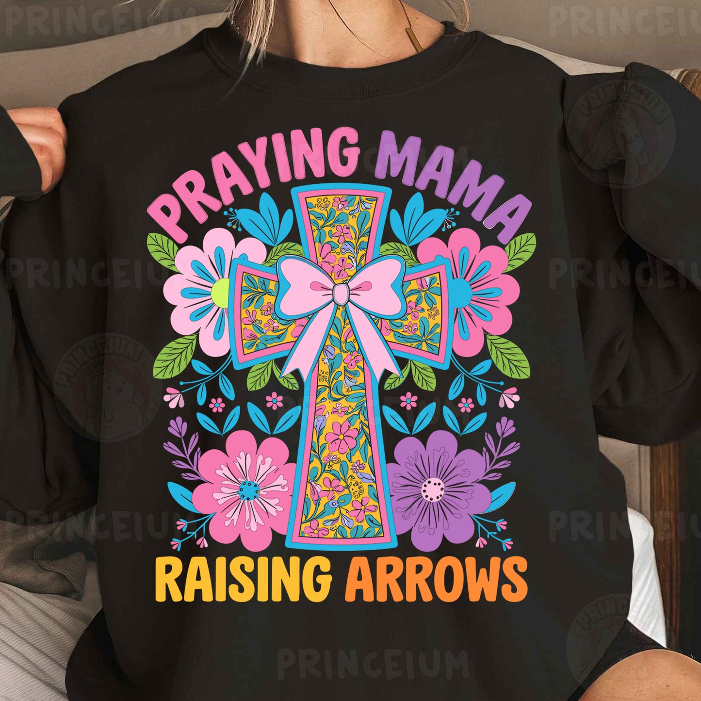 a woman wearing a black shirt that says praying mama raising arrows