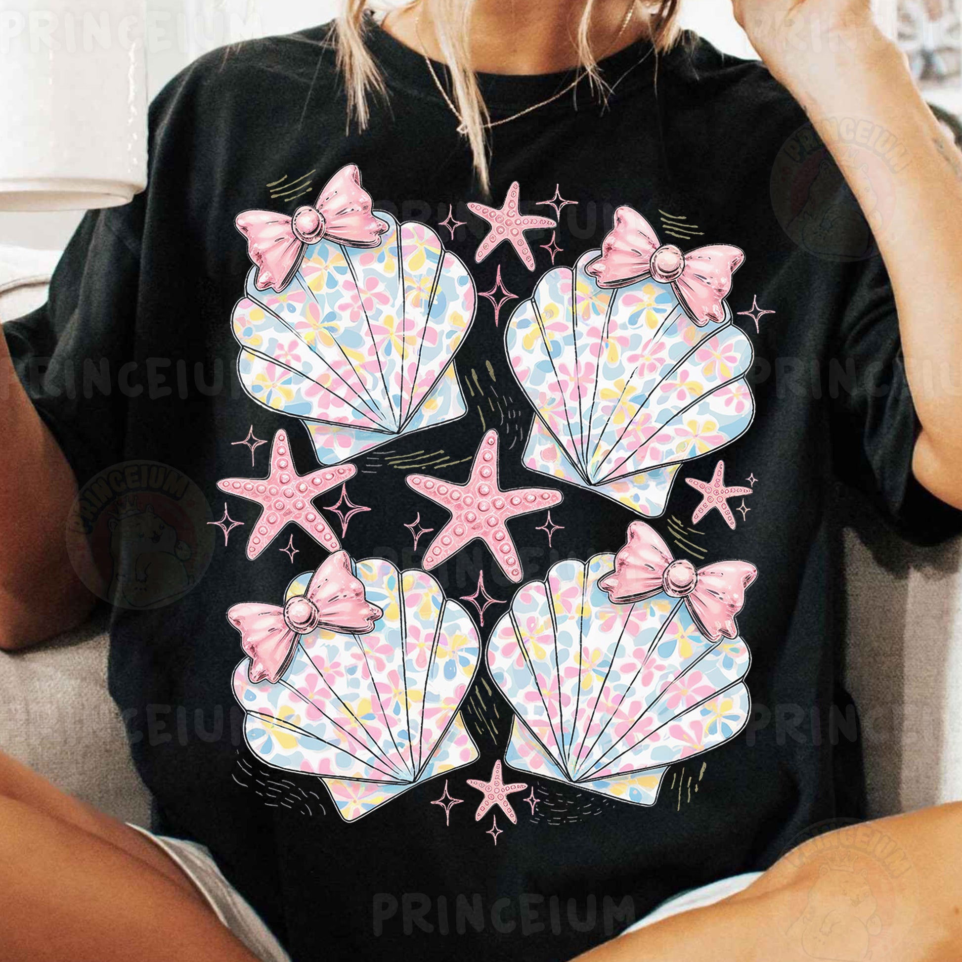 a woman sitting on a couch wearing a black shirt with pink bows and seashell
