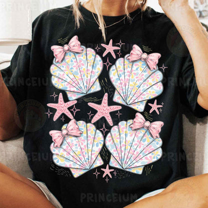 a woman sitting on a couch wearing a black shirt with pink bows and seashell