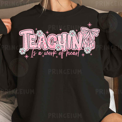 a woman wearing a black shirt that says teaching is a work of heart
