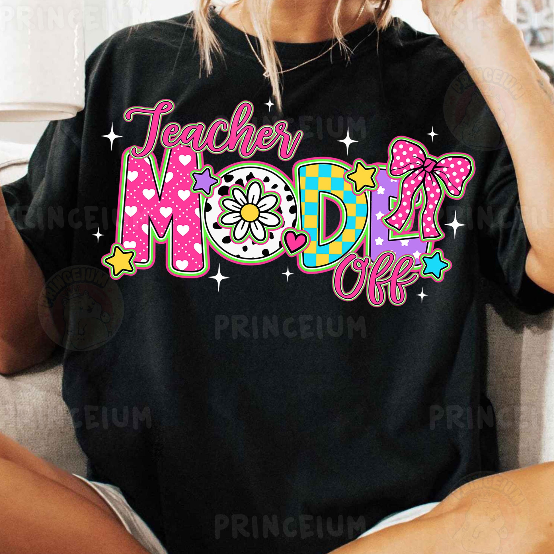 a woman sitting on a couch wearing a black teacher mom shirt