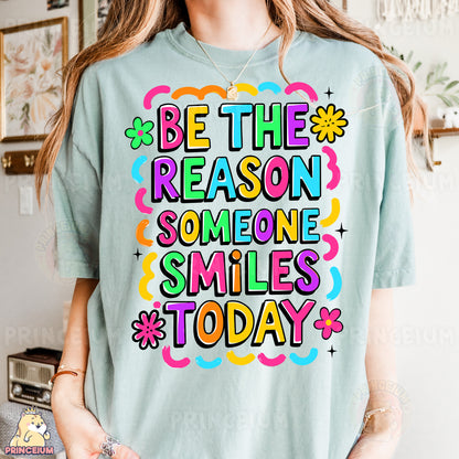 a woman wearing a t - shirt that says be the reason someone smiles today