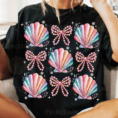 a woman sitting on a couch wearing a black shirt with pink bows and pearls