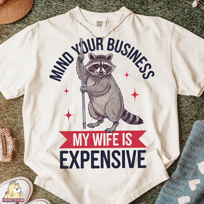 a t - shirt with a raccoon saying mind your business my wife is
