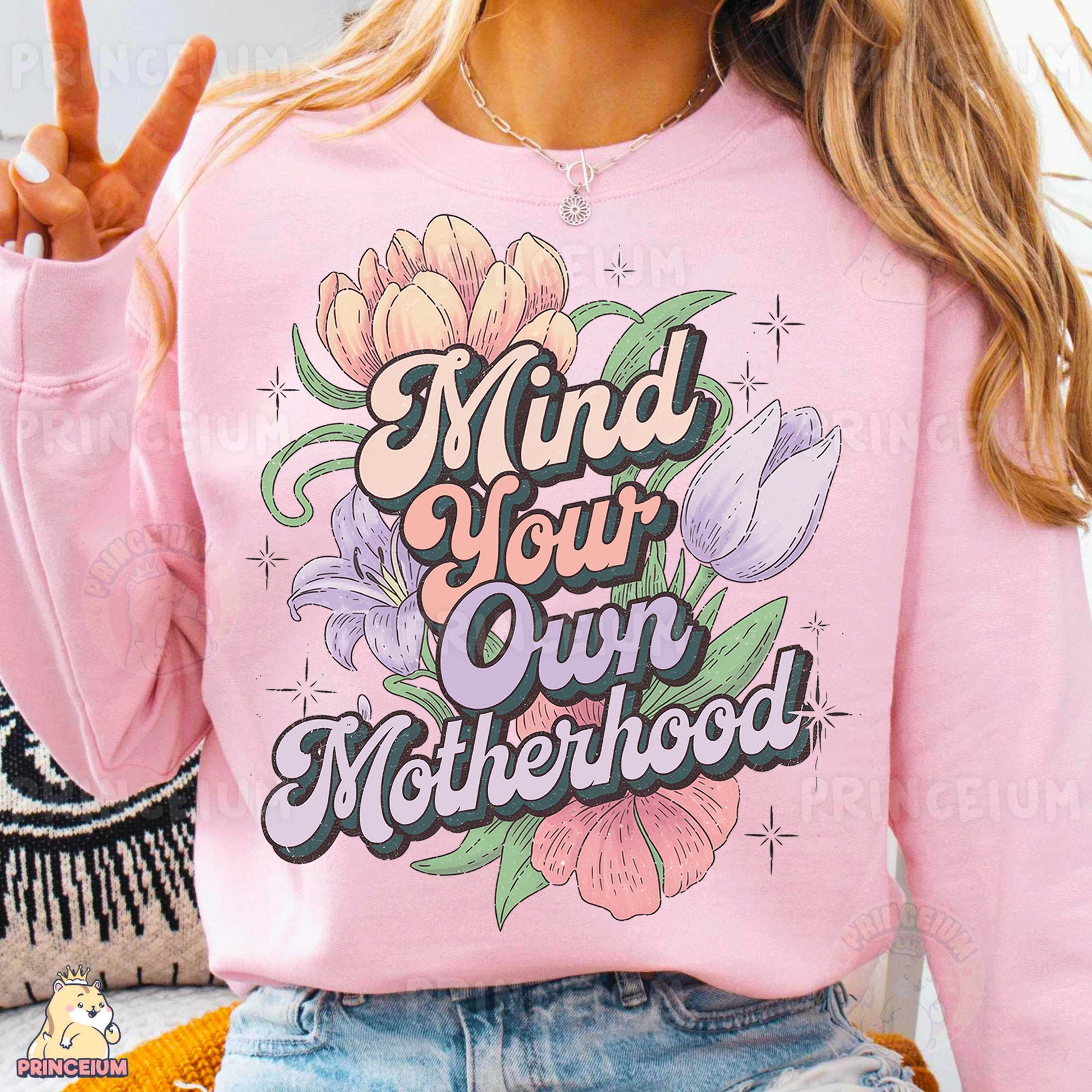 a woman wearing a pink sweatshirt that says mind your own motherhood