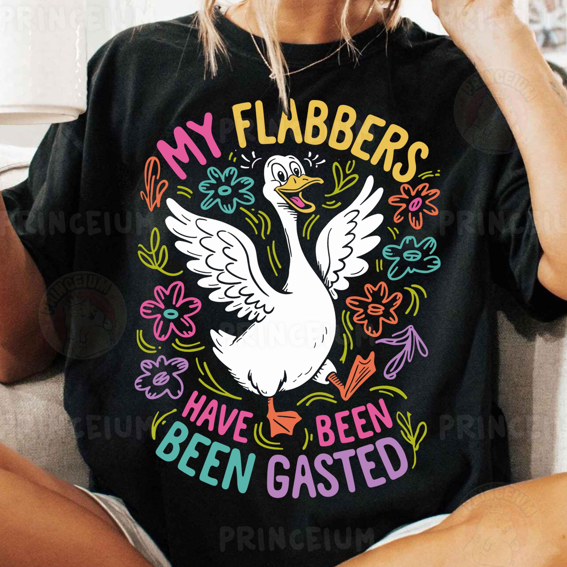 a woman sitting on a couch wearing a black shirt with a white goose on it