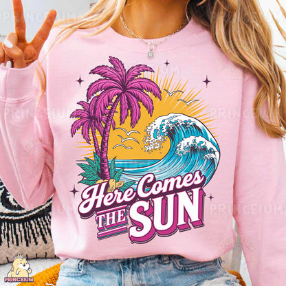 a woman wearing a pink shirt that says here comes the sun