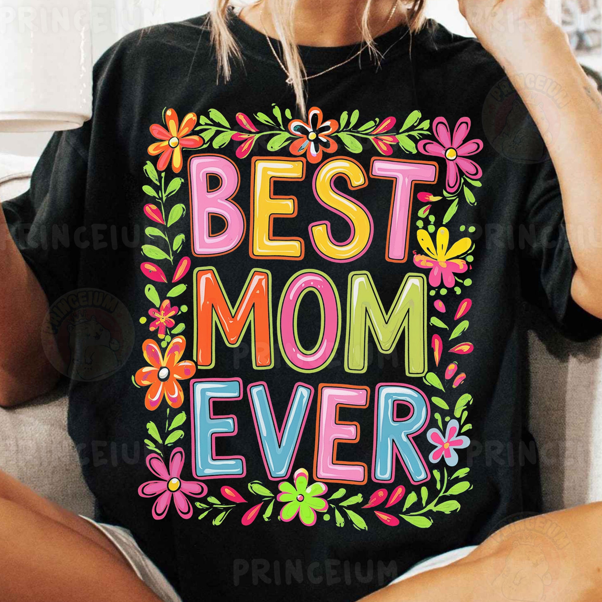 a woman sitting on a couch wearing a t - shirt that says best mom ever