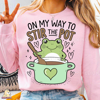 a woman wearing a pink shirt that says, on my way to stir the pot