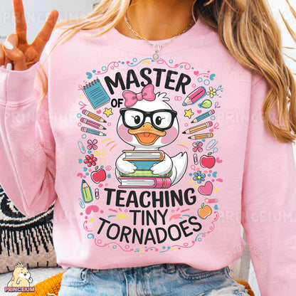 a woman wearing a pink shirt that says, master of teaching tiny tornados