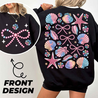 a woman wearing a black sweatshirt with pink and blue seashells on it
