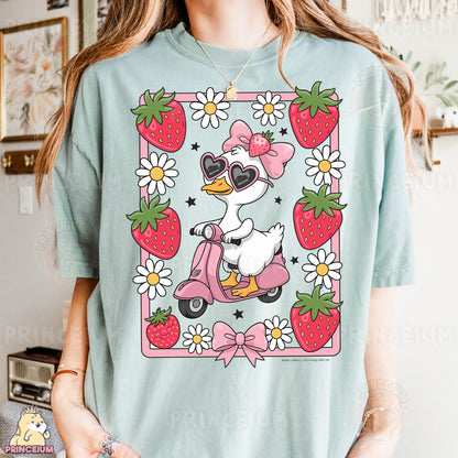 a woman wearing a t - shirt with a duck riding a scooter