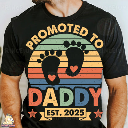 a man wearing a black t - shirt with a baby feet on it