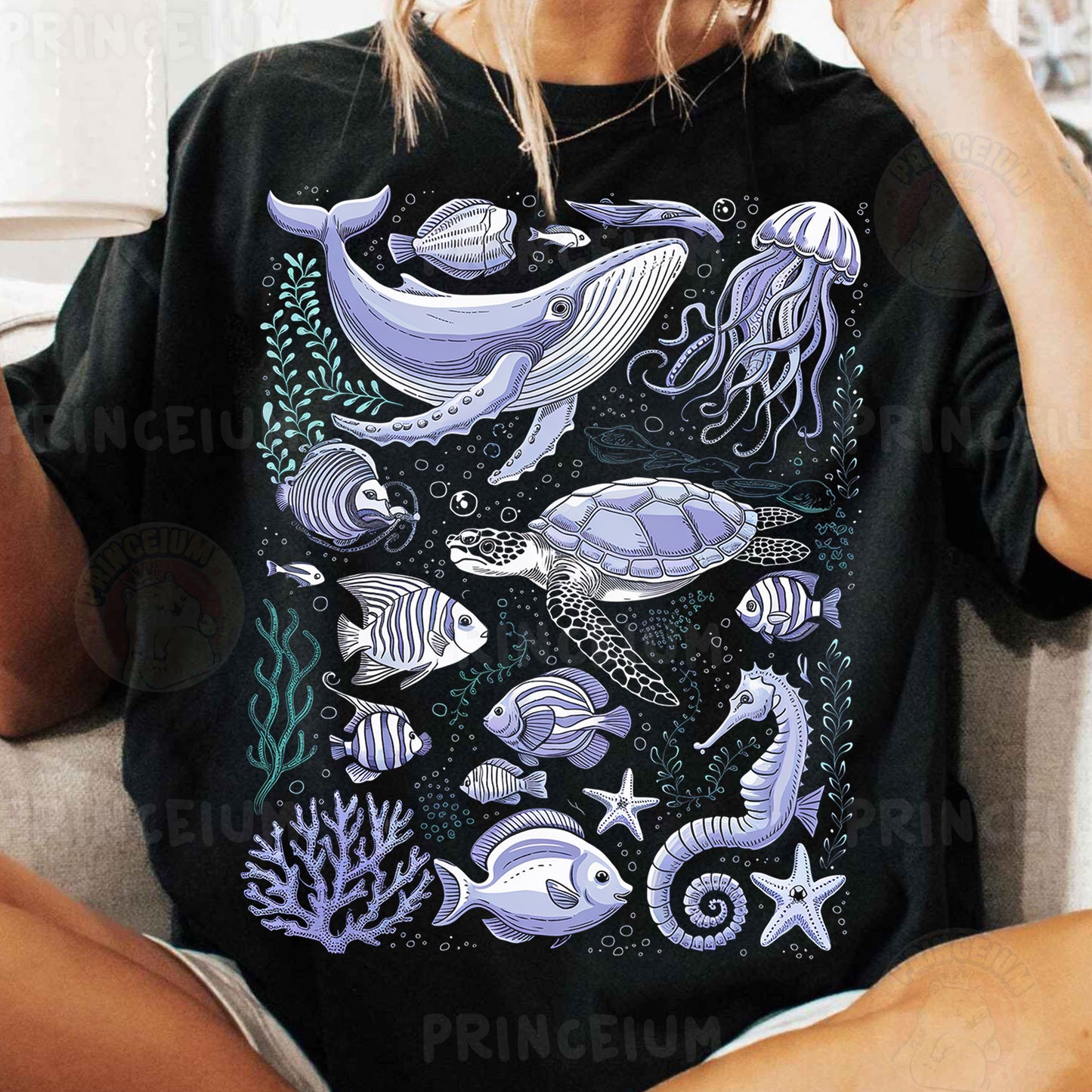 a woman sitting on a couch wearing a black shirt with sea animals on it