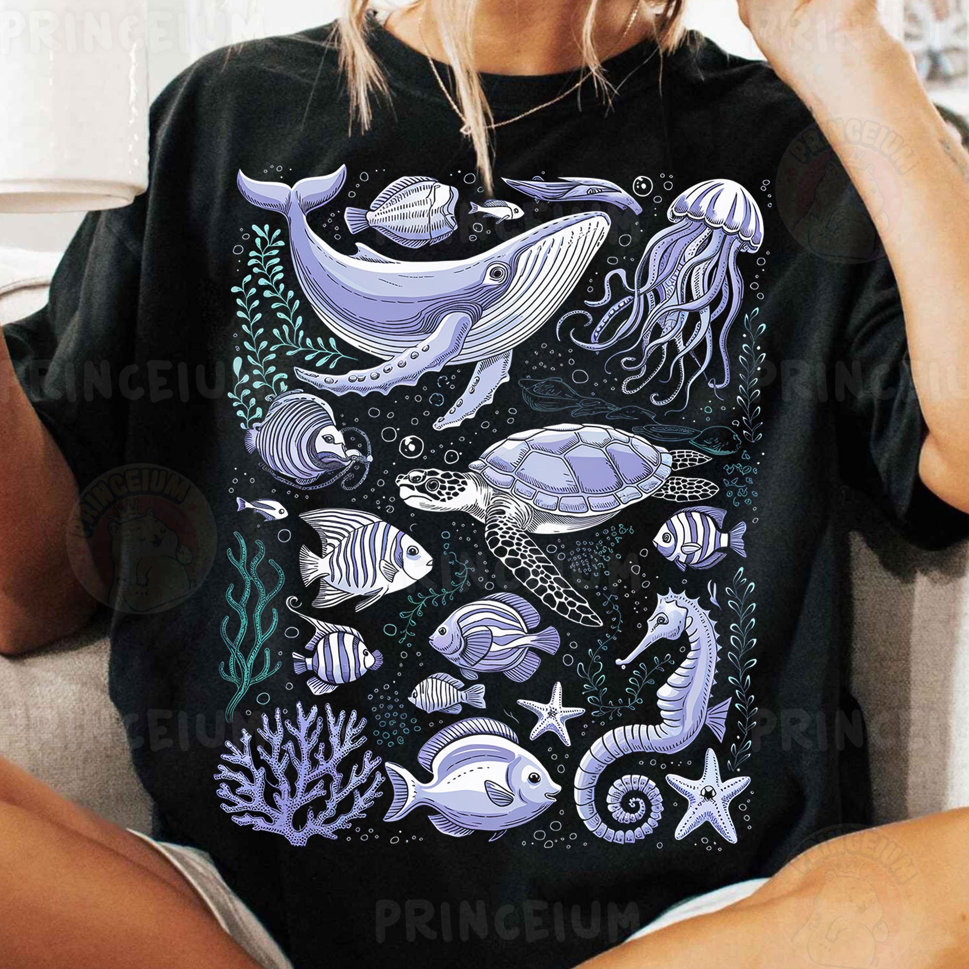 a woman sitting on a couch wearing a black shirt with sea animals on it