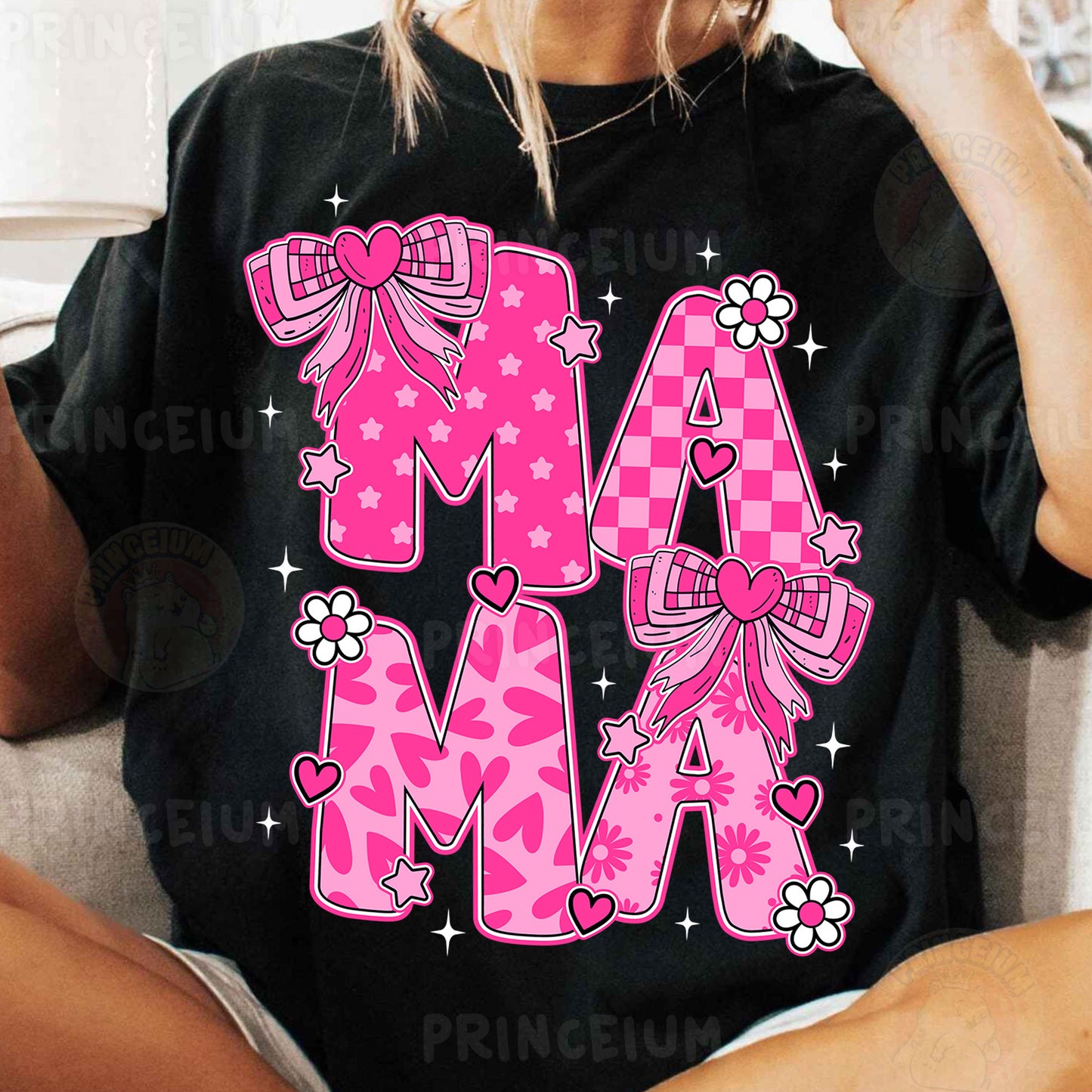 a woman sitting on a couch wearing a black shirt with pink letters and bows