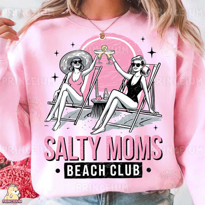 a woman wearing a pink shirt that says salty moms beach club