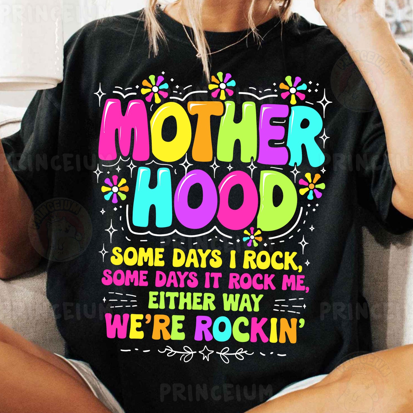 a woman sitting on a couch wearing a t - shirt that says motherhood