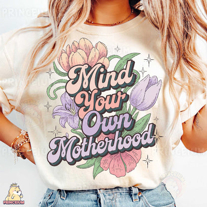 a woman wearing a t - shirt that says mind your own motherhood