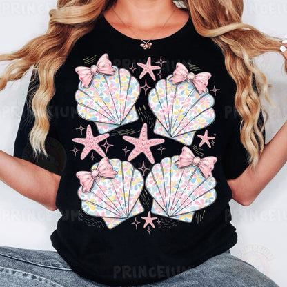 a woman wearing a black shirt with pink bows and seashells on it