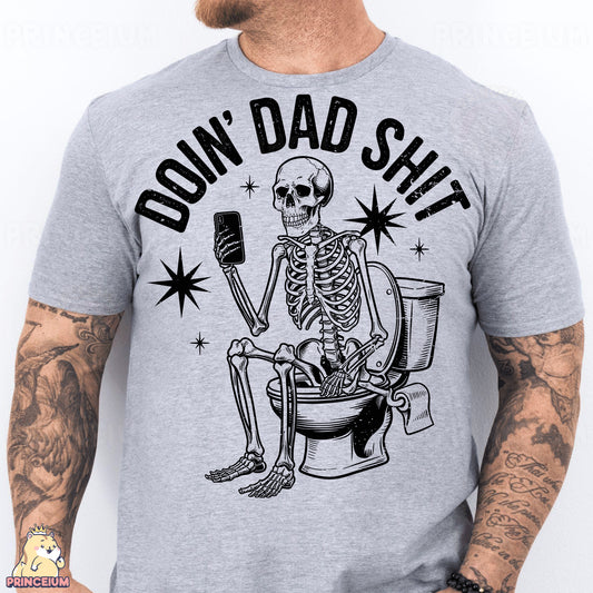 a man wearing a gray shirt with a skeleton sitting on a toilet