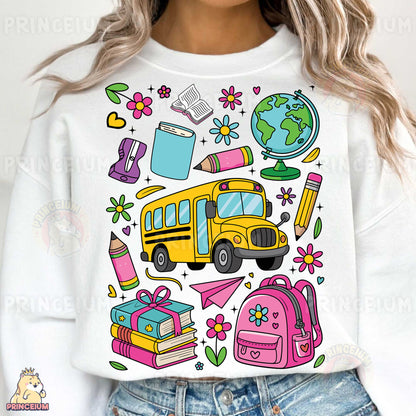 a woman wearing a white sweatshirt with school supplies on it
