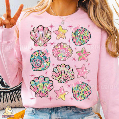 a woman wearing a pink sweater with seashells on it