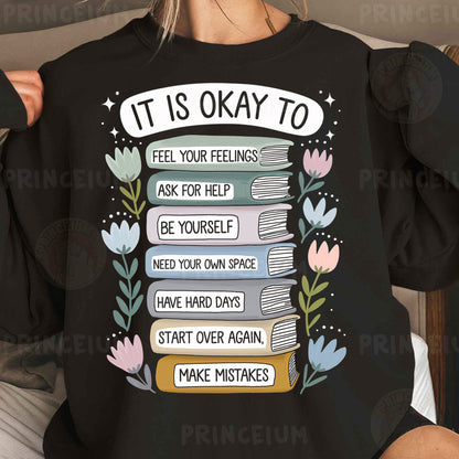 a woman wearing a black sweatshirt that says it is okay to feel your feelings ask