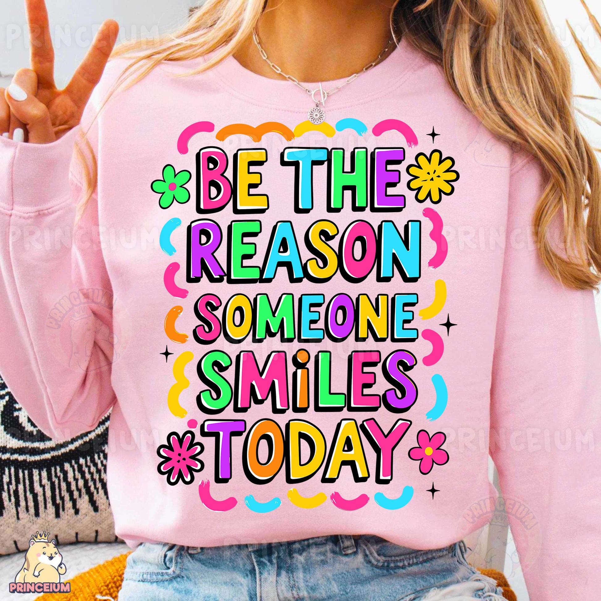a woman wearing a pink sweatshirt that says be the reason someone smiles today