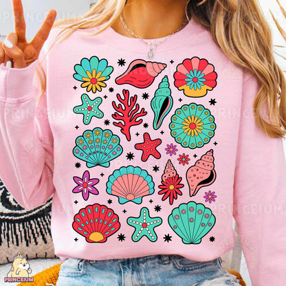 a woman wearing a pink sweater with colorful seashells on it