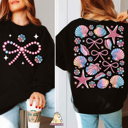 a woman wearing a black sweatshirt with pink and blue seashells on it