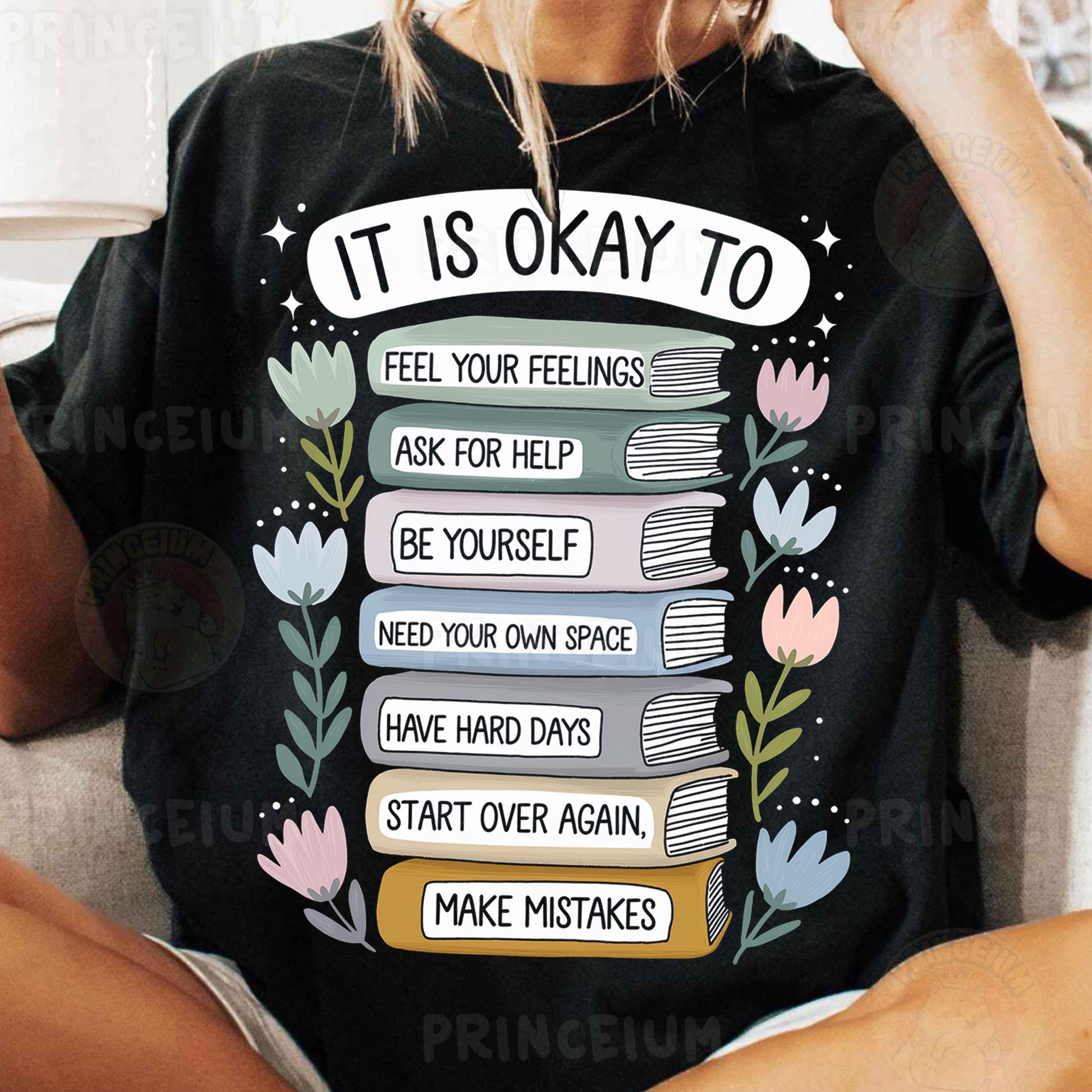 a woman sitting on a couch wearing a t - shirt that says it is okay