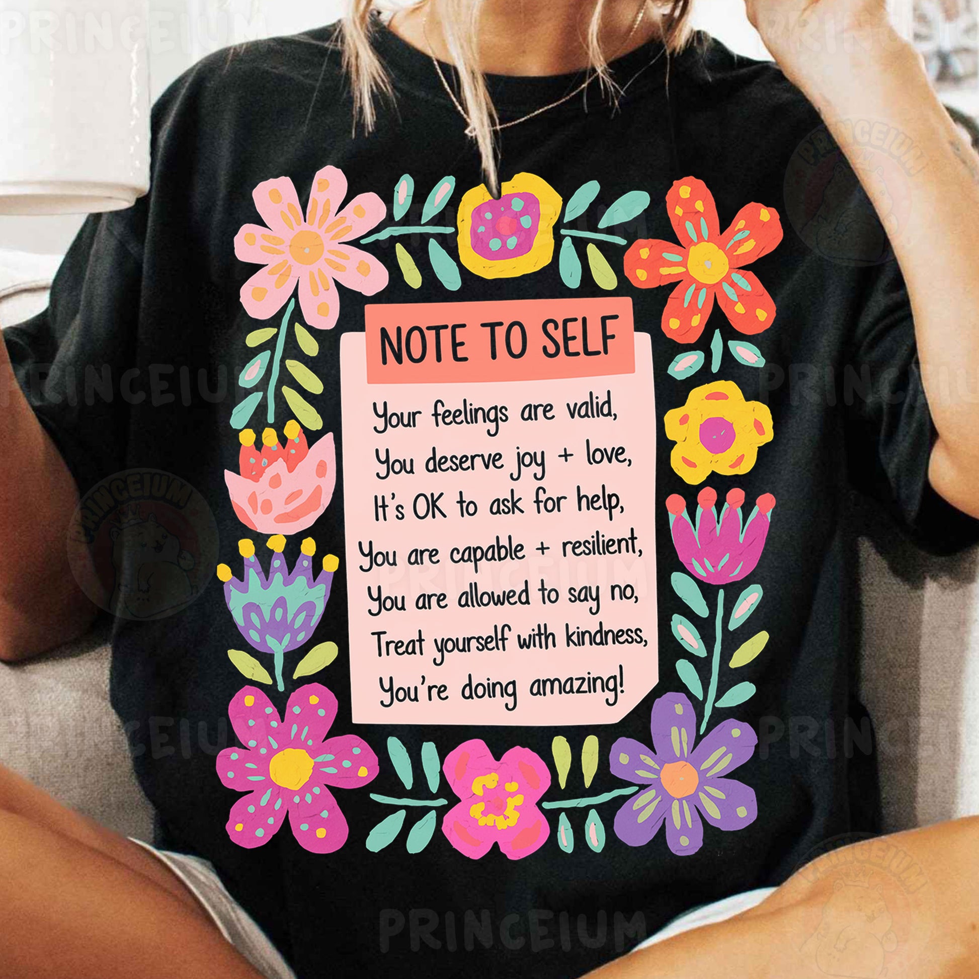 a woman sitting on a couch wearing a t - shirt with a note to self