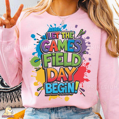 a woman wearing a pink sweatshirt that says let the games field day begin